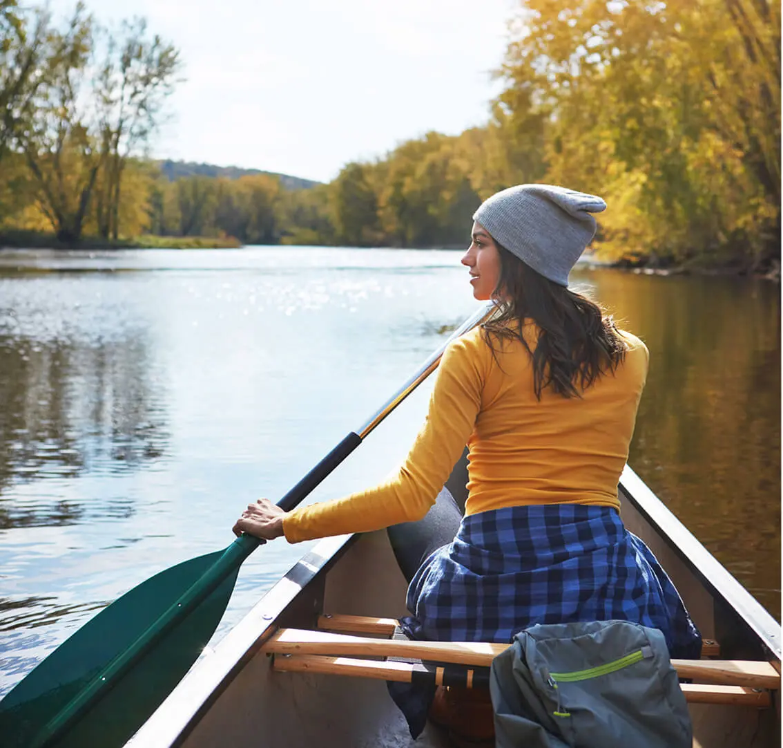Woman paddling canoe on a calm river.