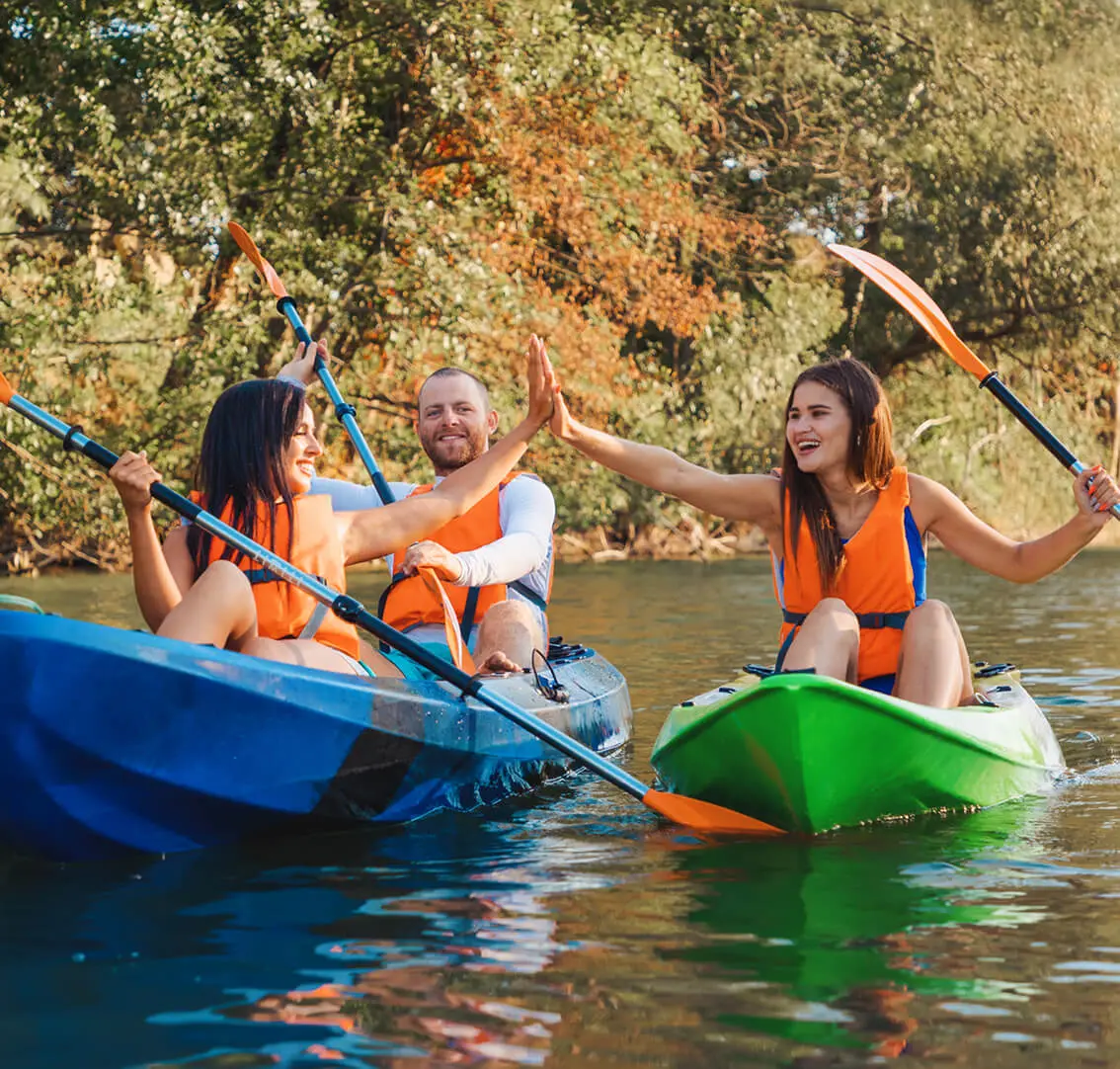 Group kayaking and high-fiving on river.