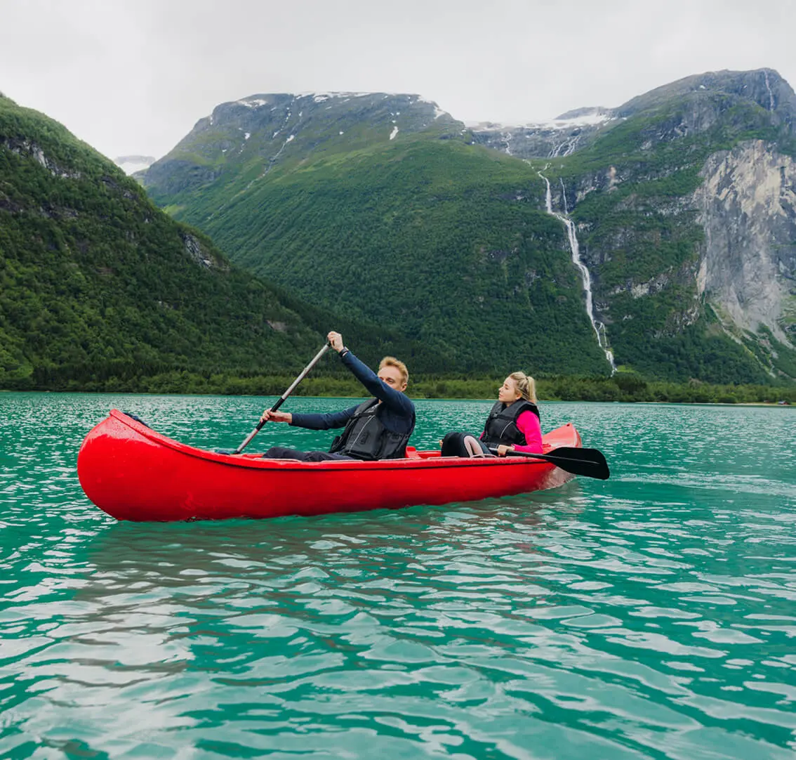 Couple kayaking on turquoise lake with mountains.